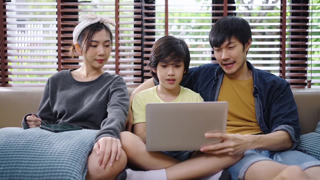 家人在笔记本电脑上对着镜头微笑交谈。幸福的家庭在家里讲视频电话。视频素材