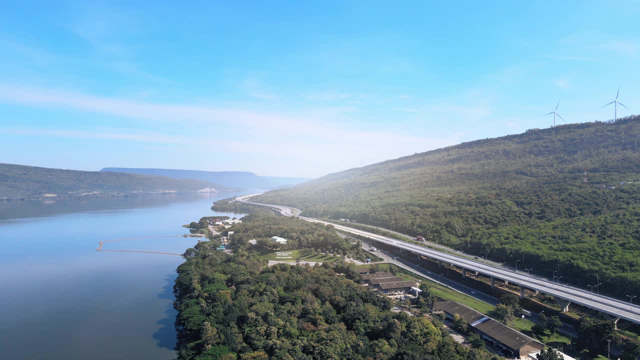 空中无人机超延时延时美丽的高速公路在绿色森林与大坝在公路的一边之间的山。视频素材