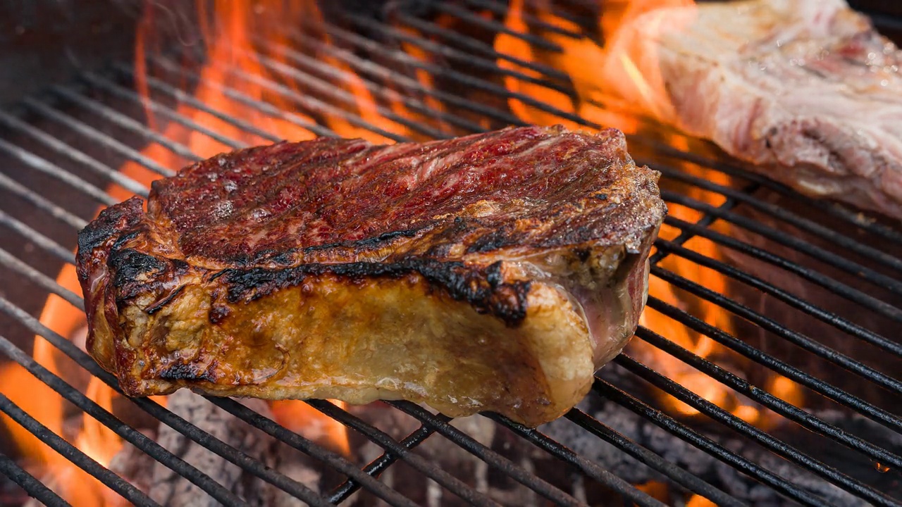 多汁的striploin牛排与完美的烧烤标志被烤在明火烧烤视频素材