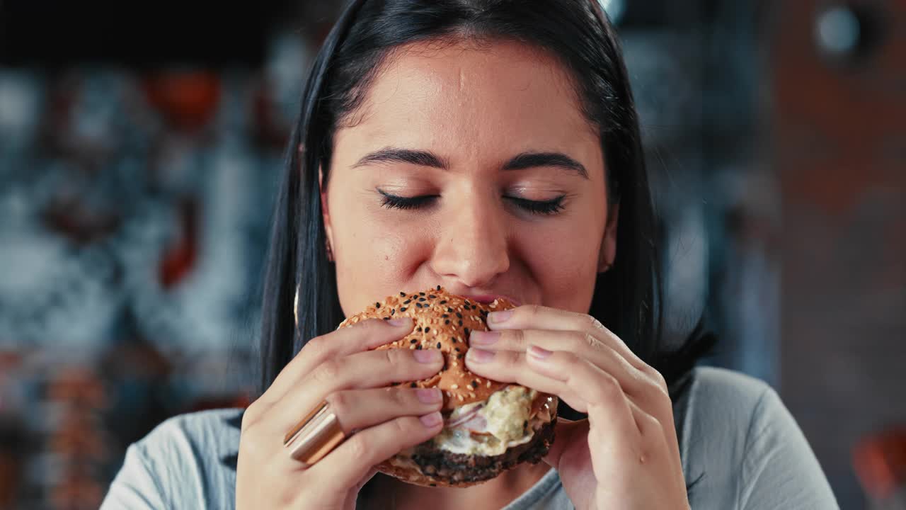 一个年轻女子在餐厅里吃汉堡的4k视频视频下载