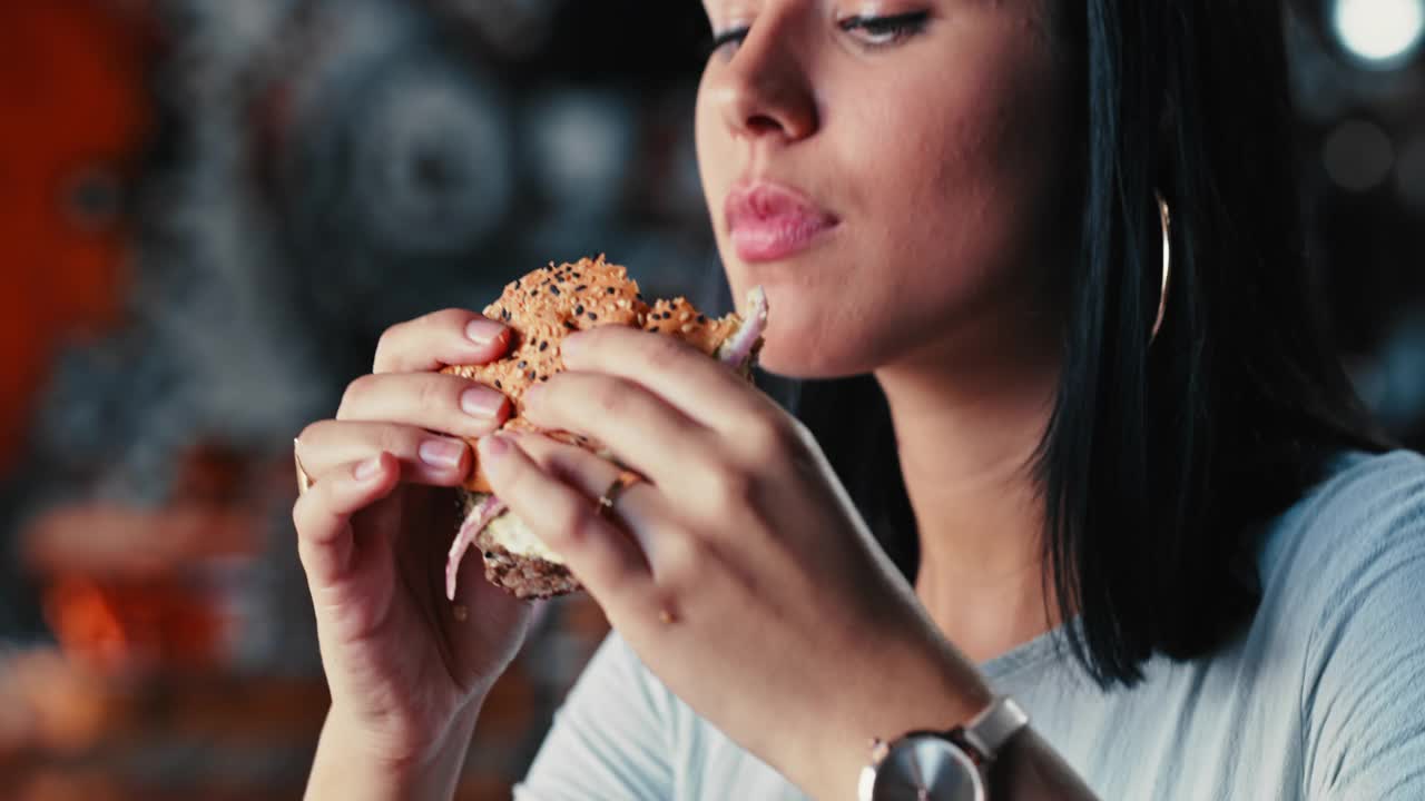一个年轻女子在餐厅里吃汉堡的4k视频视频素材