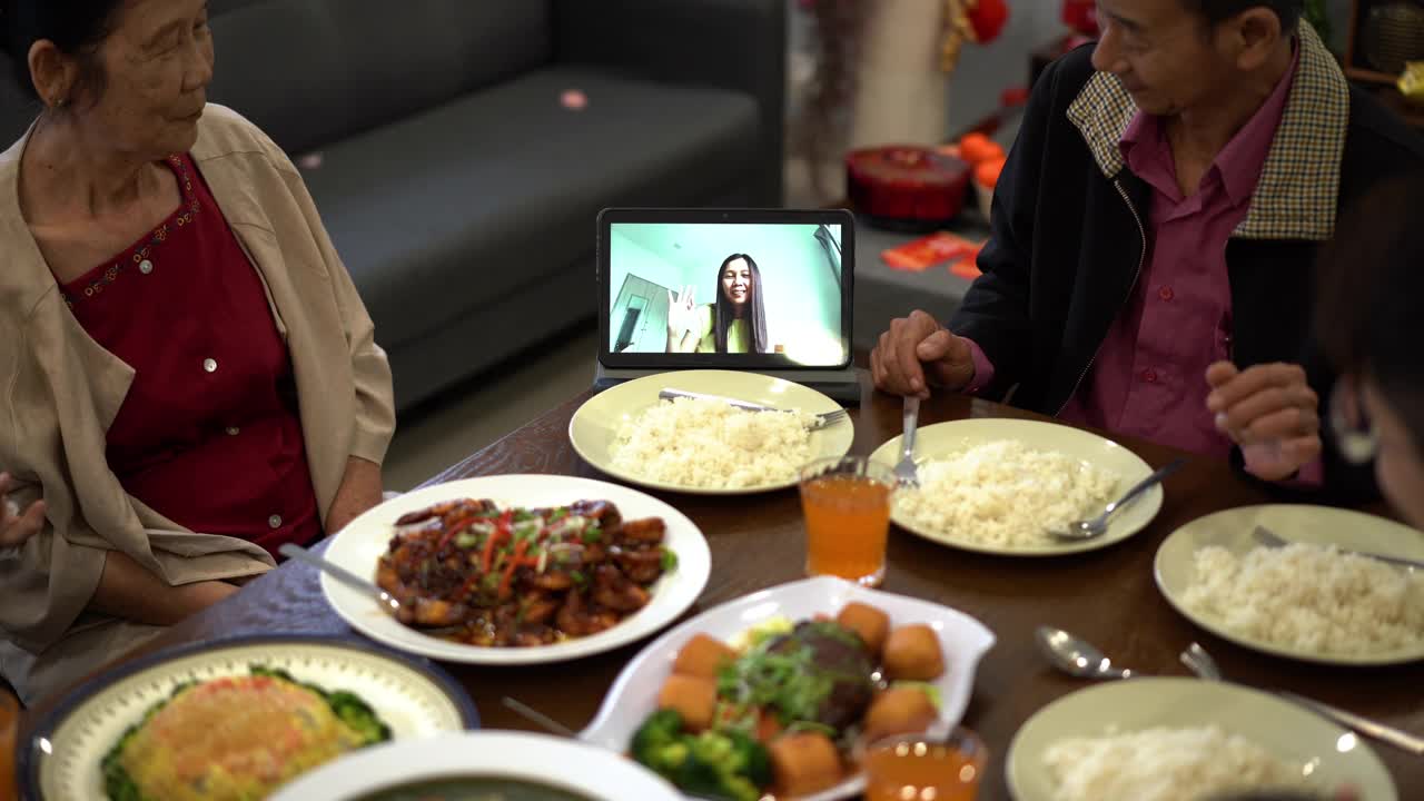 快乐的亚洲华人家庭在团圆饭期间用数码平板电脑视频给亲戚打电话视频下载