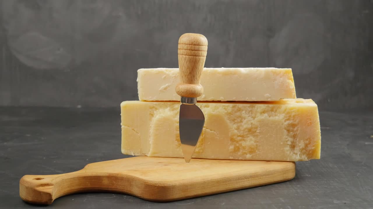 帕尔玛。两种帕尔马干酪。帕尔玛刀。帕尔马奶酪放在木板上。24个月和48个月视频素材