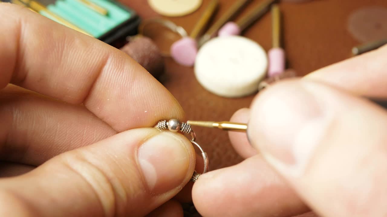 专业的珠宝商用一种特殊的工具抛光银质耳环。一位专业雕刻师制作一件珠宝视频下载