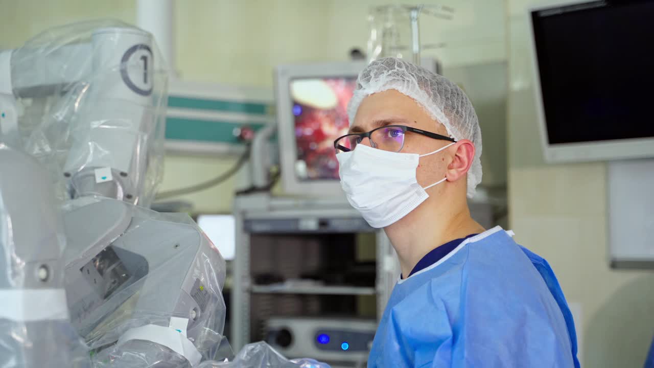 专家使用手术机器人进行手术。在当代手术室里，一位身穿医疗制服、戴着口罩的年轻外科医生的肖像。视频素材