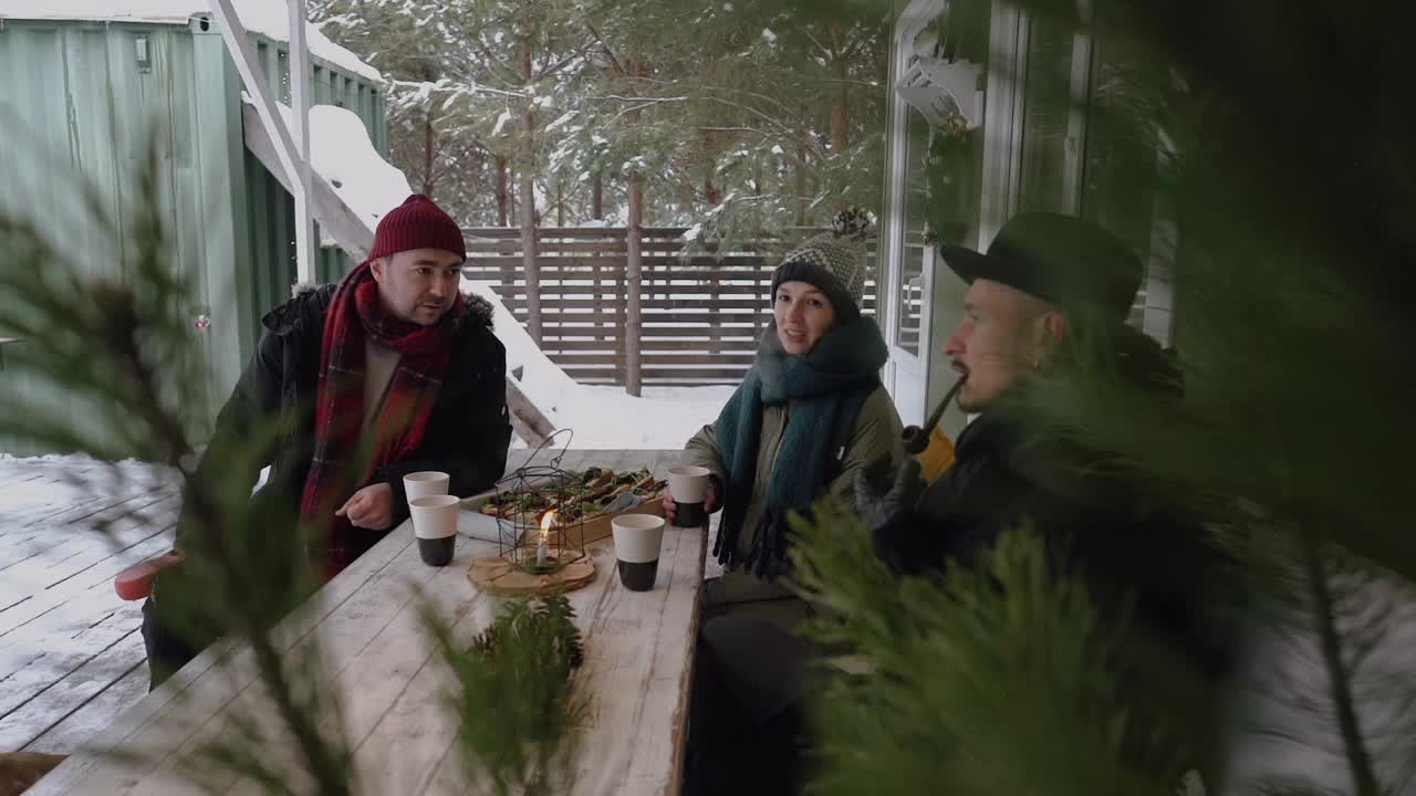 好朋友坐在下雪的阳台上，聊天，喝咖啡视频下载