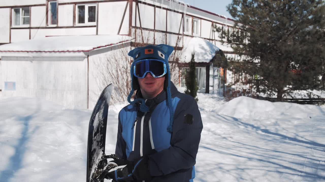 快乐的滑雪板运动员把滑雪板举过头顶放在背后视频下载