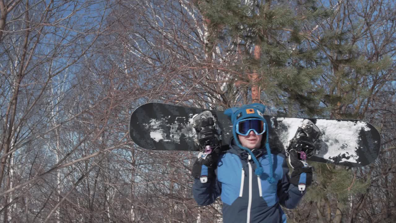 一名滑雪者拿着滑雪板爬过森林，到达坡顶视频下载