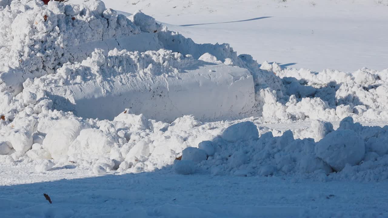 慢动作视频。在一个阳光明媚的冬日，一辆蓝色的拖拉机带着铲子清扫街道上的积雪视频下载