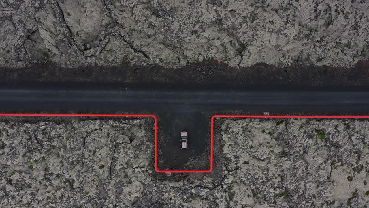 无人机视频显示，一辆越野车沿着穿越冰岛熔岩平原的地热管道行驶视频下载