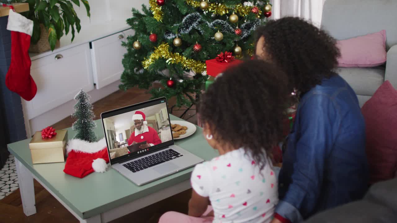 快乐的非洲裔美国母亲和女儿在圣诞节用笔记本电脑与圣诞老人视频通话视频下载