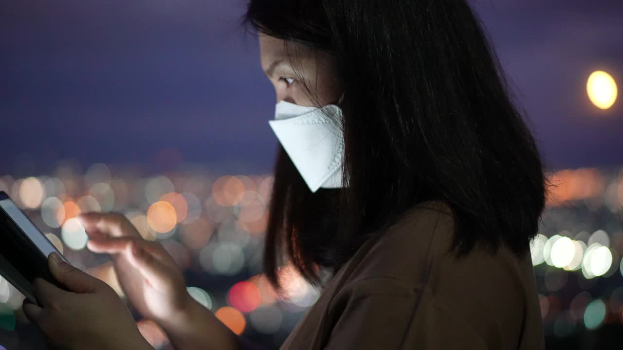 女人在夜里用手机用圆灯散景在城里视频素材