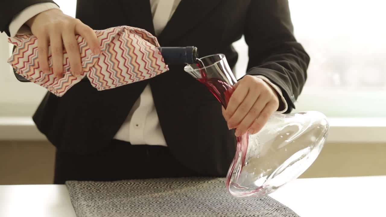 在餐馆里，侍酒师将葡萄酒倒入酒壶中视频素材