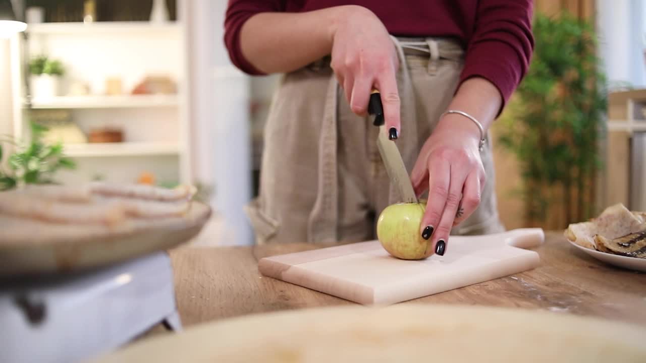一位妇女准备新鲜的果汁，在砧板上切苹果视频下载