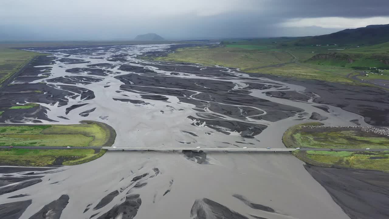 冰岛，一架无人机从横跨一条辫状河的桥梁上的汽车上向后移动视频下载