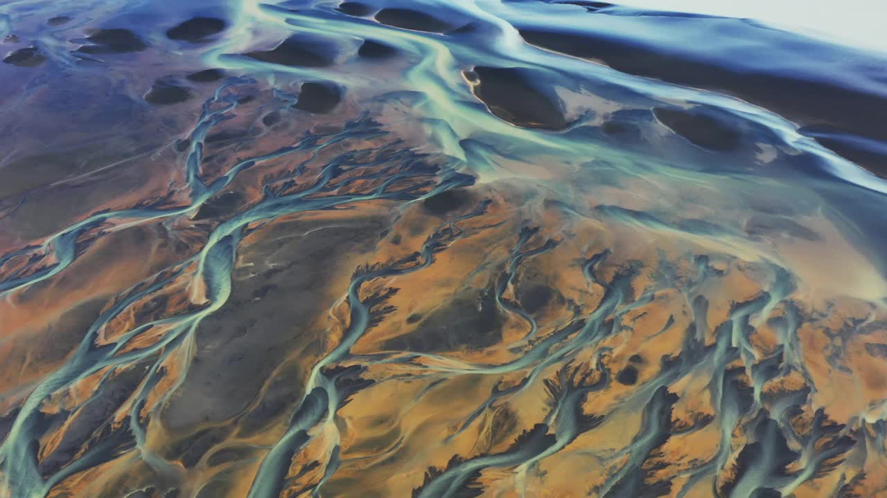 高角度的平移镜头显示了一条辫状河流过冰岛的火山地貌视频素材