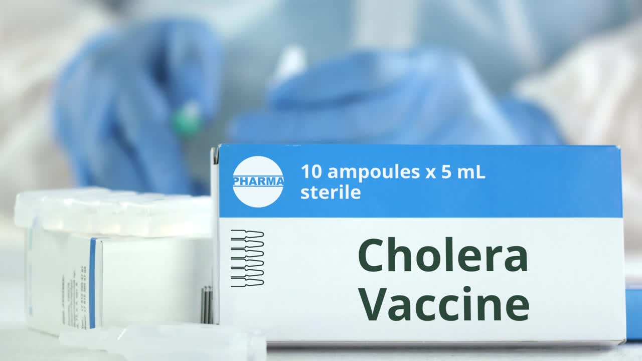 工作实验室助理旁边的桌子上放着霍乱疫苗安瓿瓶，盒子上有虚构的标志视频素材