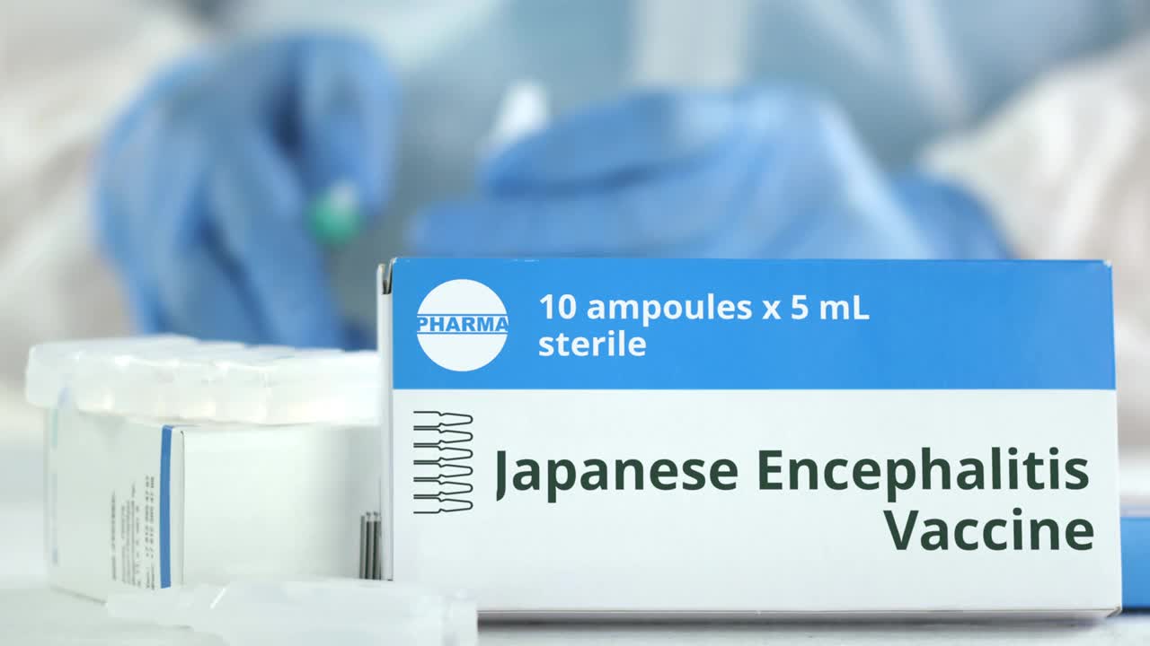 盒子上有日本脑炎疫苗在桌上防止实验室助手模糊。虚构的phaceutical标志视频素材