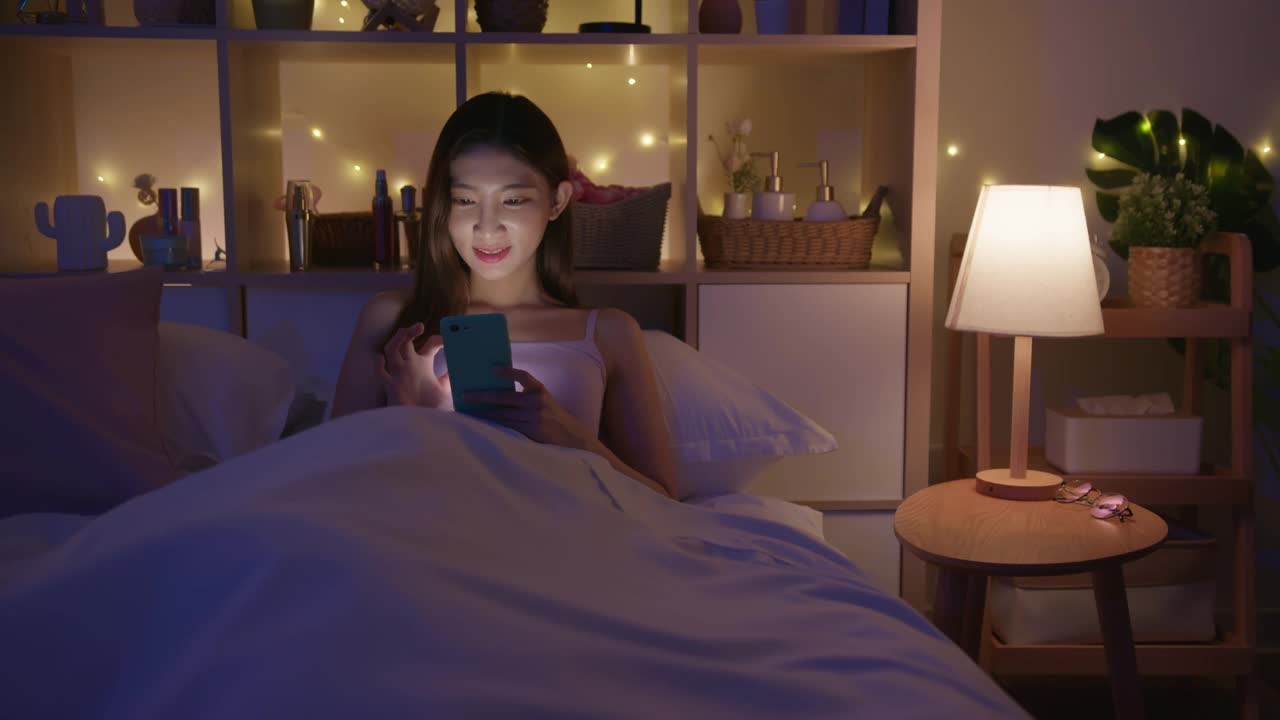 女人在床上用智能手机视频下载
