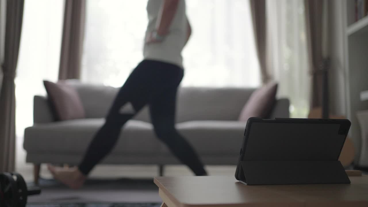 女性在家锻炼和练习用平板电脑燃烧脂肪视频下载