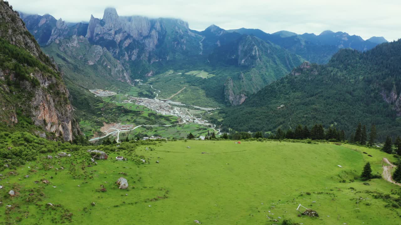 无人机拍摄的山谷、绿色草地和民居，中国甘南州洛克路视频下载
