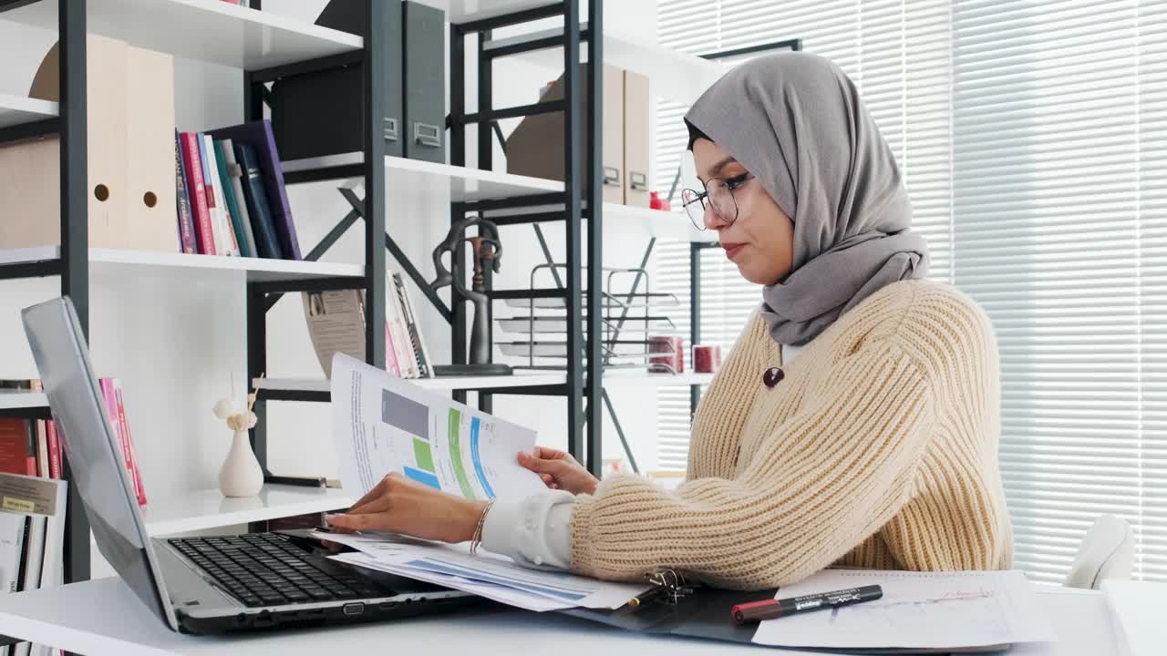 戴着头巾、头戴耳机的伊斯兰女士用笔记本电脑进行视频通话视频下载
