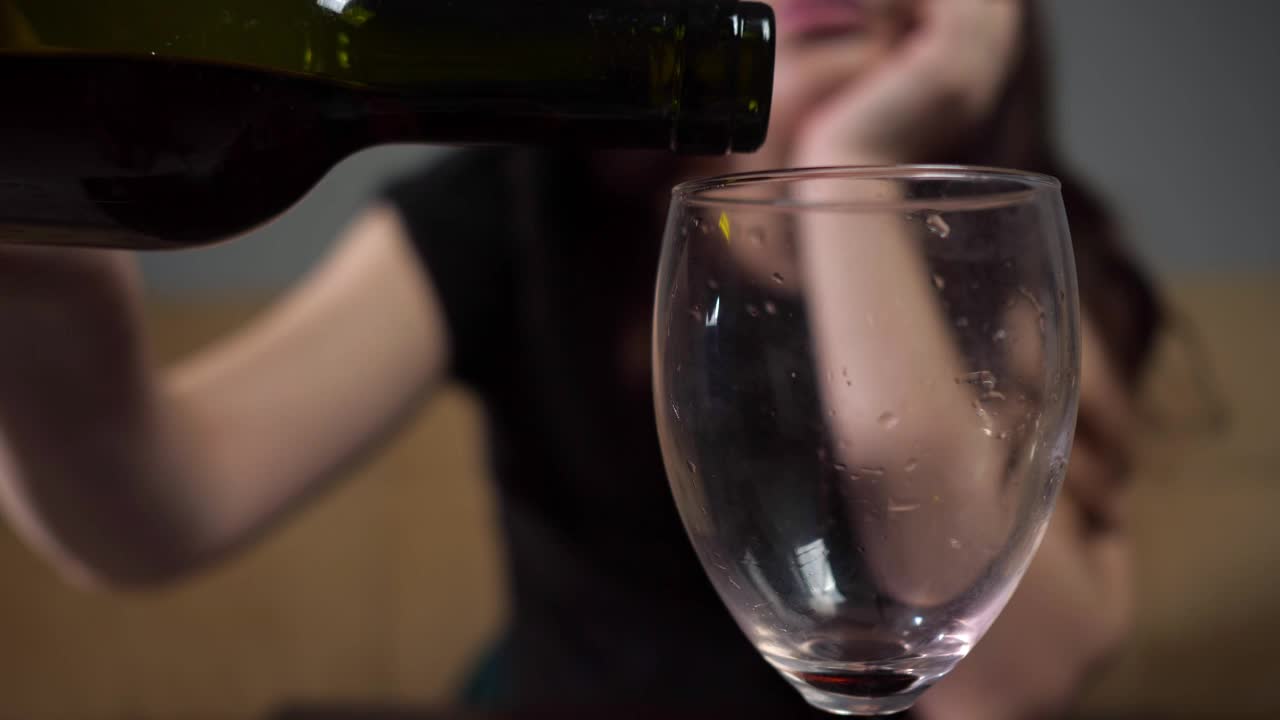 醉醺醺的女人带着悲伤的表情往酒杯里倒酒视频下载