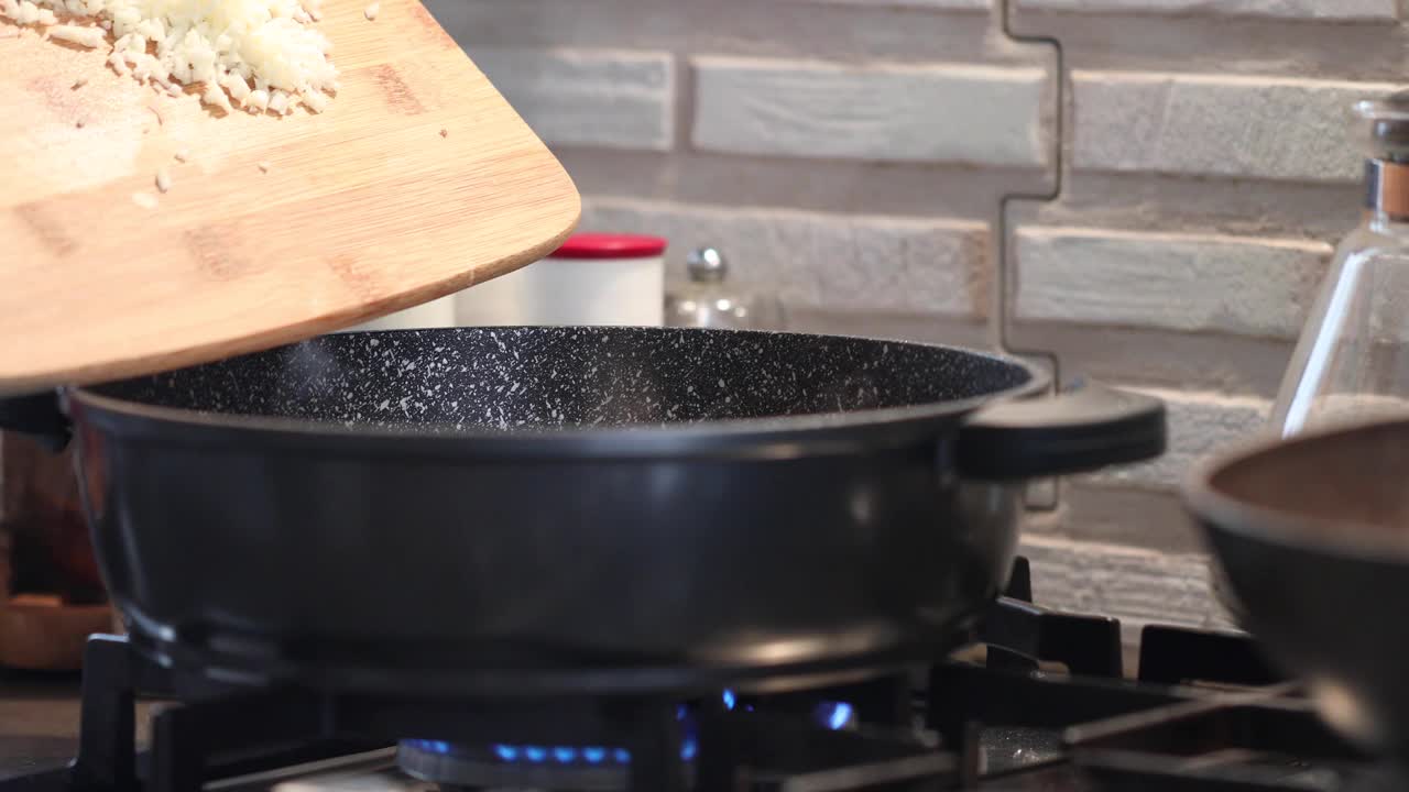 厨师将洋葱倒入火上的煎锅中视频素材