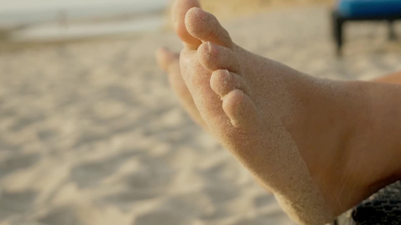 男孩的脚覆盖着沙滩椅上的沙子，生活方式的概念。视频下载