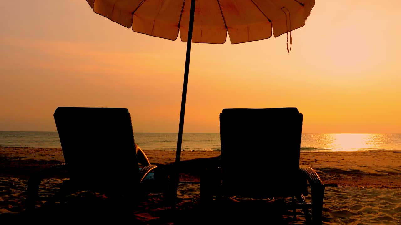 在泰国华欣日出的白色沙滩上，沙滩椅和遮阳伞。视频下载
