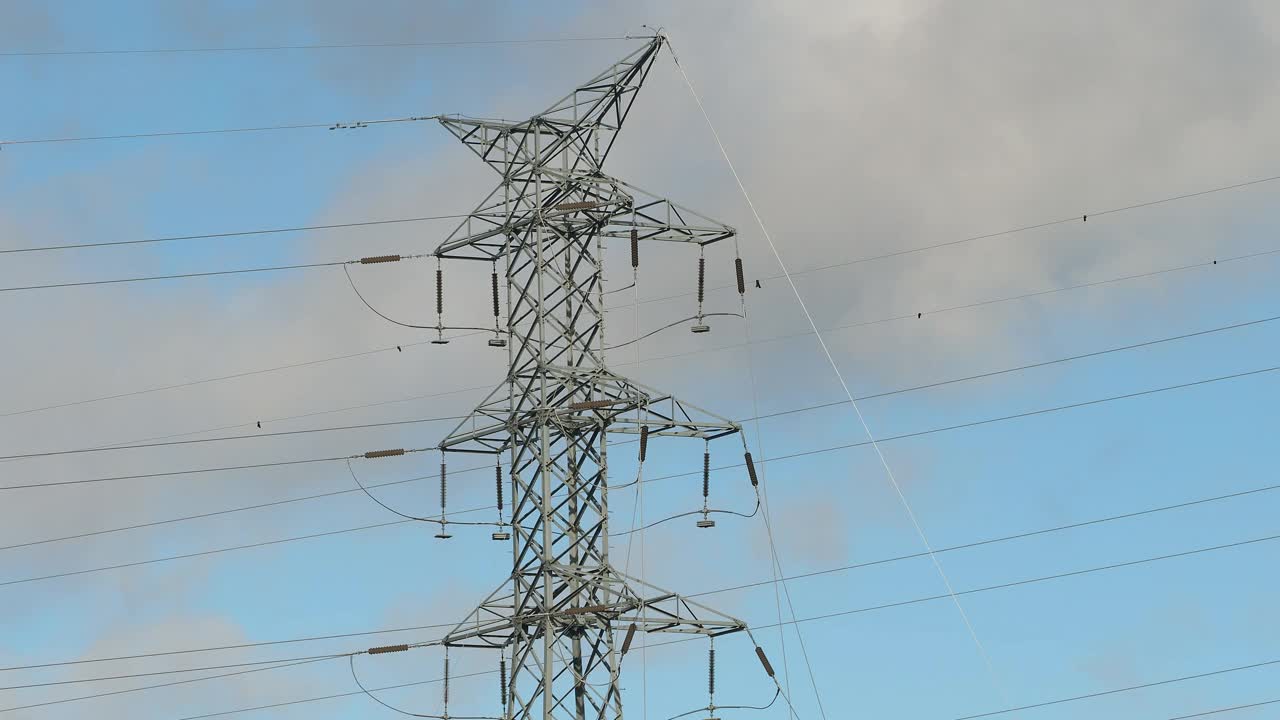 高压电塔的剪影在天空与移动的云。视频下载