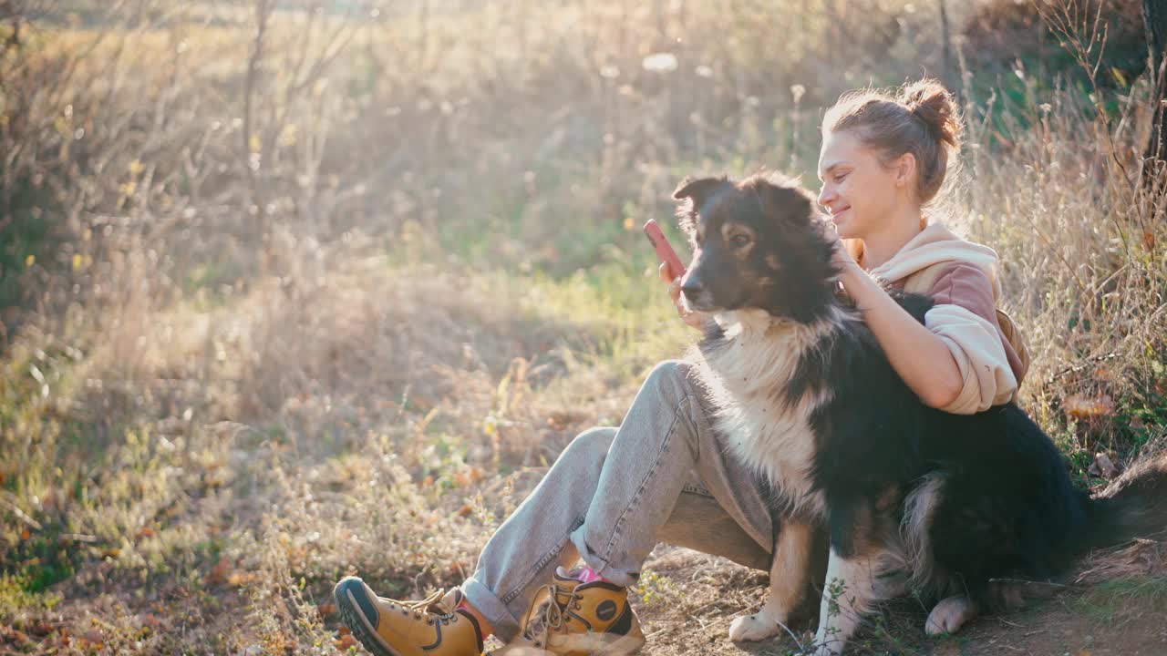 一位年轻的成年女子和她的狗狗坐在山上自拍视频素材