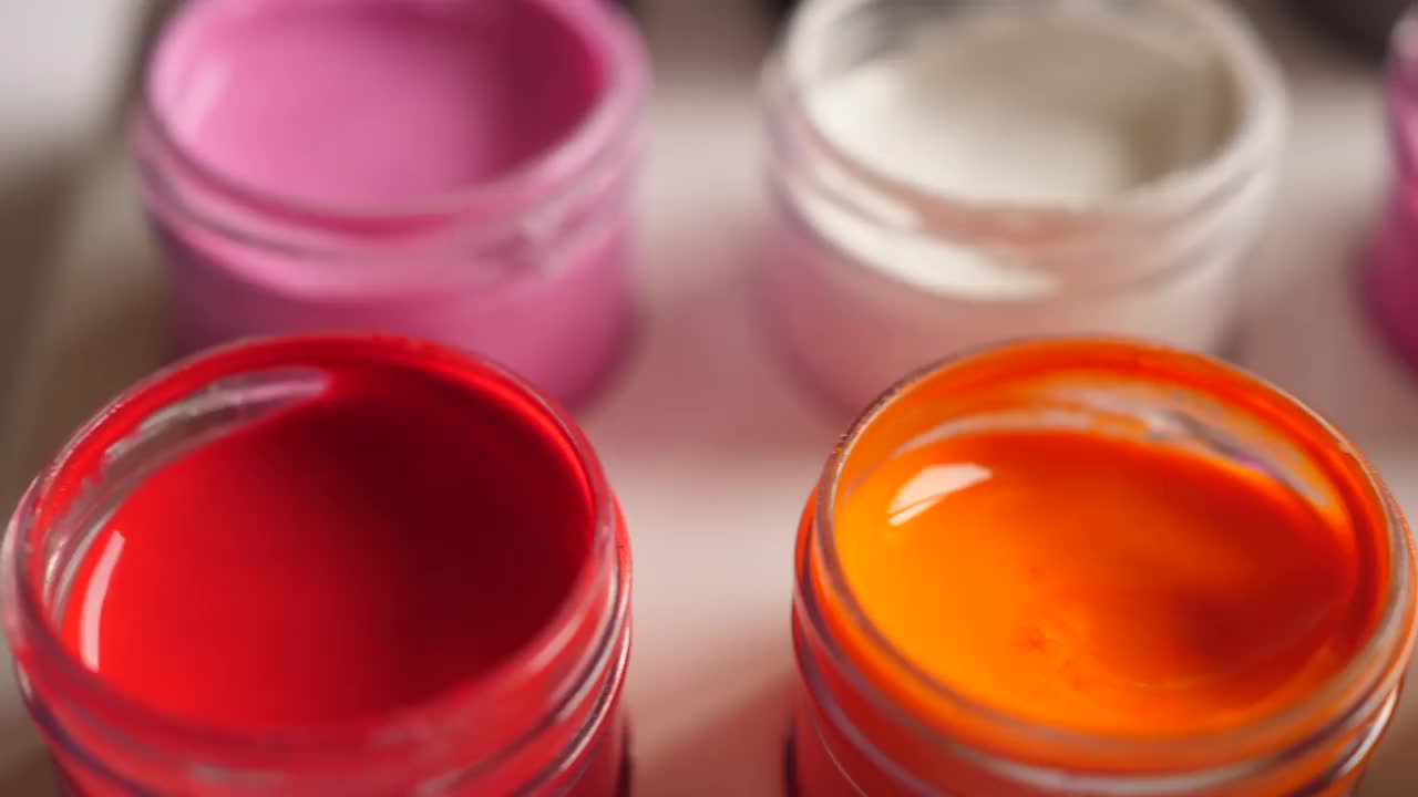 设置水粉颜料在罐子明亮的颜色近距离。一套彩色水粉画在塑料罐上。多莉拍摄多色背景。多色油漆背景。爱好绘画艺术。视频素材