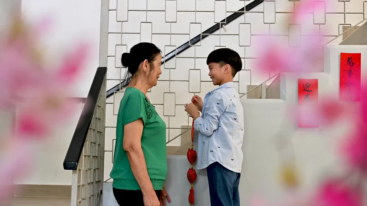 快乐的奶奶和小孙子一起装饰他们的房子过中国新年视频素材