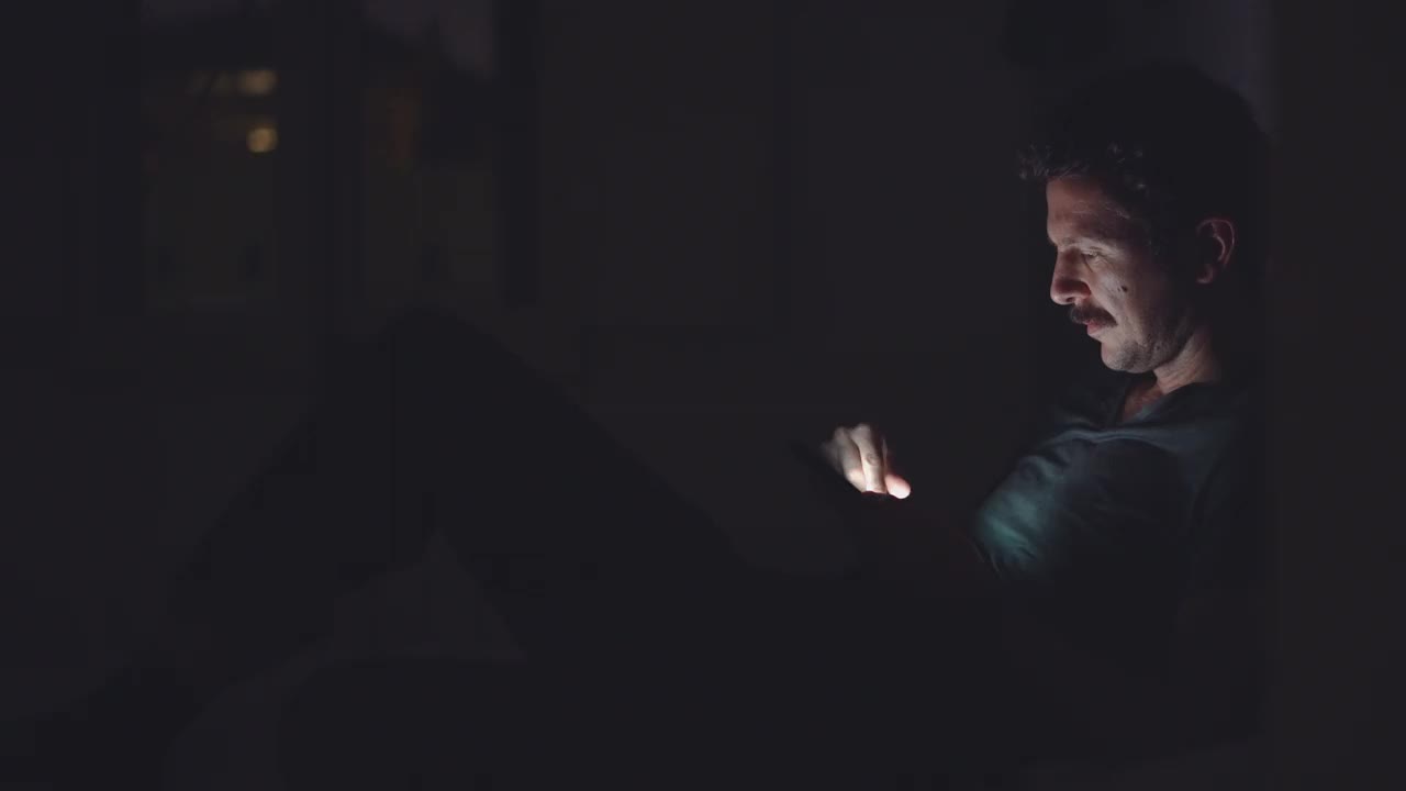 一个男人在深夜使用她的智能手机。视频素材