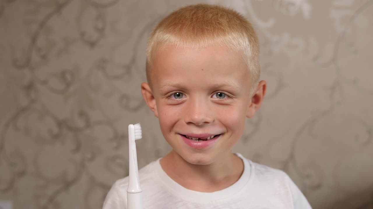 一个小男孩在家里用电动牙刷的特写。视频下载