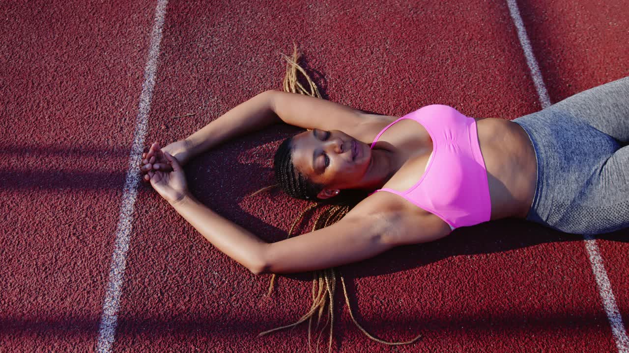 年轻的非裔美国女运动员躺在跑道上视频下载