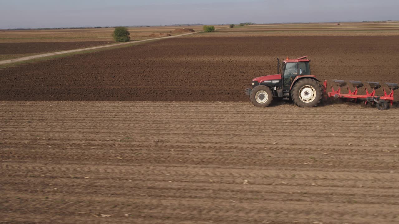 农民用拖拉机在工业农田中耕作，作物农田为播种季节做准备的航拍视频下载