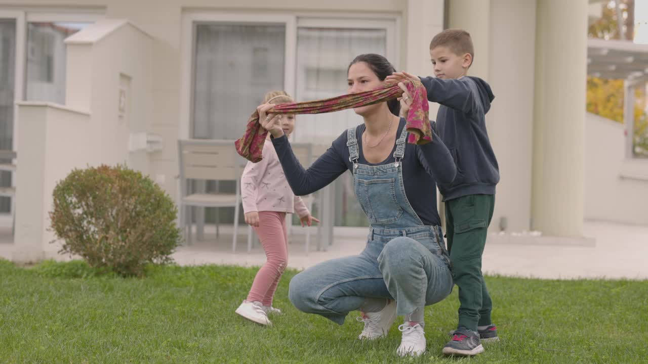 年轻的母亲和两个孩子准备在后院玩捉迷藏视频下载