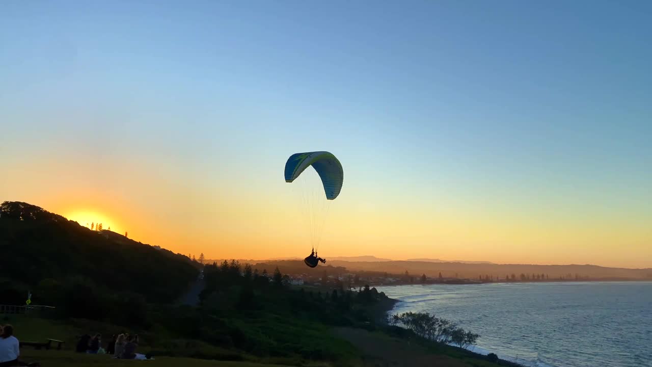 滑翔伞漂浮到日落在海洋边缘视频下载