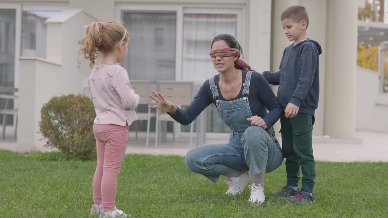 年轻的母亲和两个孩子在后院玩捉迷藏视频下载