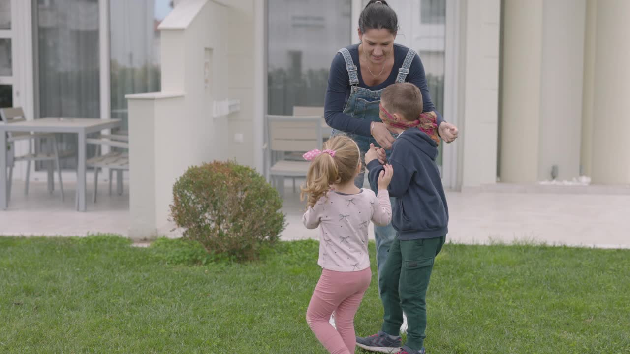年轻的母亲和两个孩子在后院玩捉迷藏视频下载
