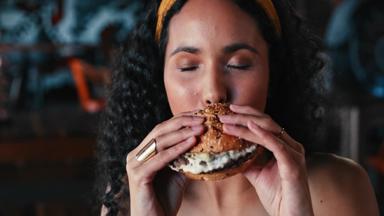 一个年轻女子在餐厅享用汉堡的4k视频视频素材