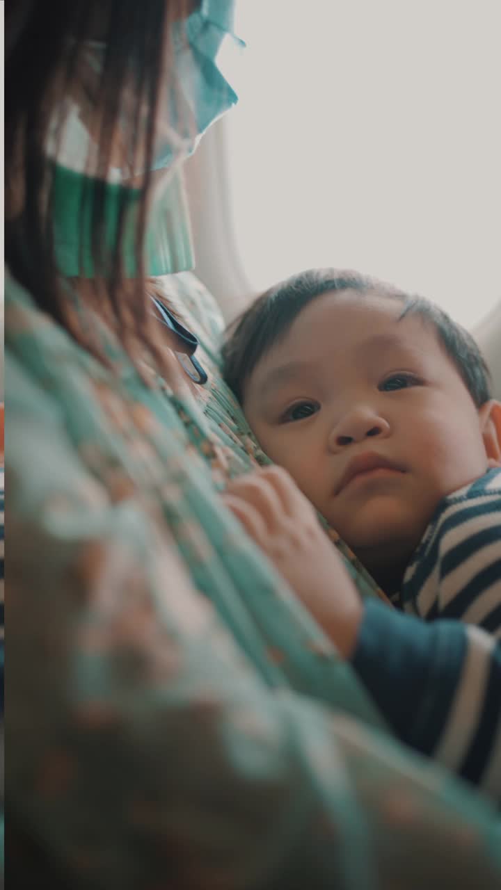 乘飞机旅行时，男孩睡在母亲的怀里。视频素材