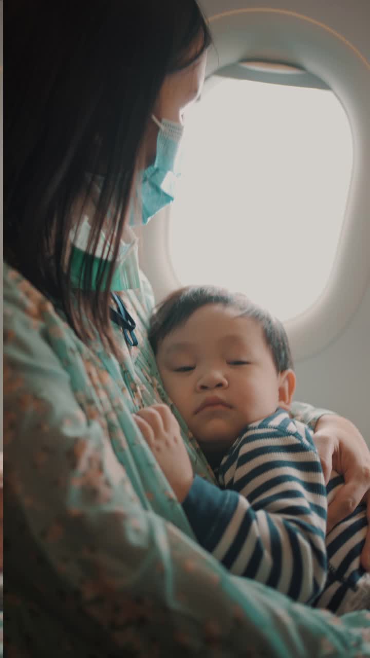 乘飞机旅行时，男孩睡在母亲的怀里。视频素材
