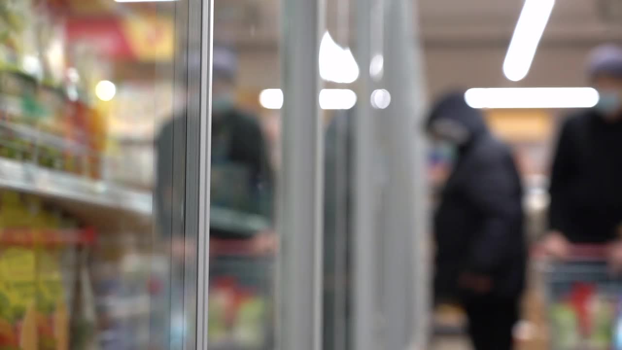 在超市里推着手推车的戴着口罩的人视频素材