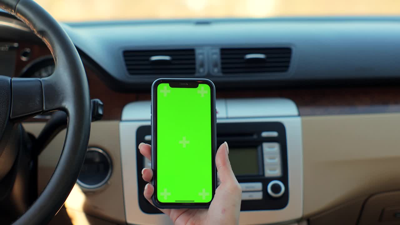 看女人手拿绿色屏幕智能手机在车里。概念:旅行方向，地址搜索，信息，位置，商务。后视图。视频素材