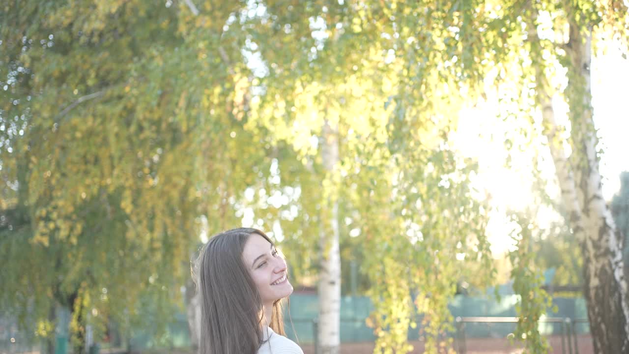 在公园外面，微笑的女性享受秋天的慢动作视频视频素材