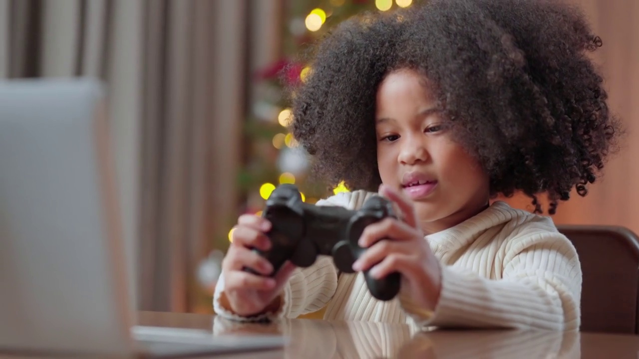 悲伤的非裔美国女性感觉不好趴在桌子上，年幼的女儿在网上玩电子竞技游戏而输掉比赛，幽默的孩子花时间在家里的游戏机视频下载