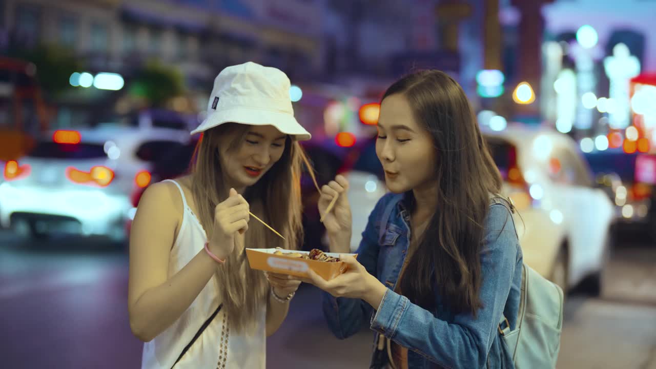 两个年轻女人在夜市吃东西视频素材